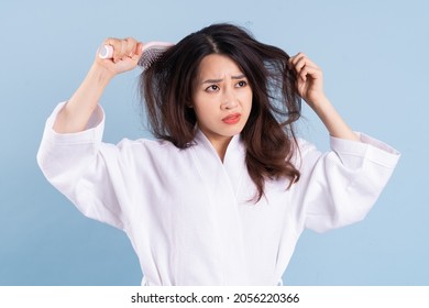 Young Asian woman wearing bathrobe on blue background