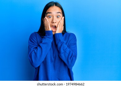 Young Asian Woman Wearing Casual Winter Sweater Afraid And Shocked, Surprise And Amazed Expression With Hands On Face 