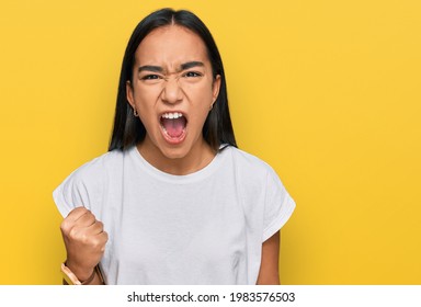 Young asian woman wearing casual white t shirt angry and mad raising fist frustrated and furious while shouting with anger. rage and aggressive concept.  - Shutterstock ID 1983576503