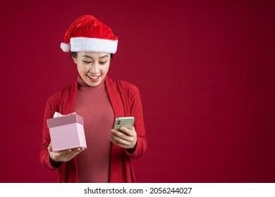 Young Asian woman wearing christmas hat on red background