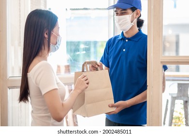 Young Asian woman wearing face mask receiving food and drink package from delivery service company staff at home for prevent coronavirus infection, Food delivery during covid-19 outbreak. - Powered by Shutterstock