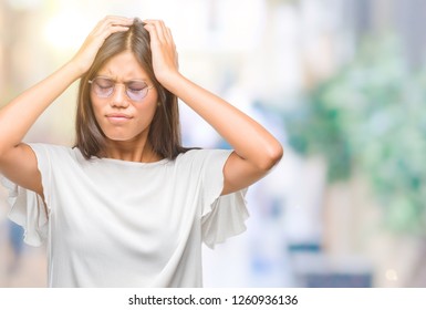 頭痛と片頭痛に苦しむ、分離型背景に眼鏡をかけた若いアジア人女性。手を頭の上に置いて。