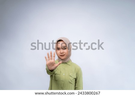 Young Asian woman wearing hijab showing stop sign at Copy Space Advertising Your Text, Standing Isolated Over white Studio Background