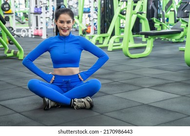 Young Asian Woman Wearing Sportware Sitting In Gym, Break After Hard Workout. A Healthy Woman Lifestyle