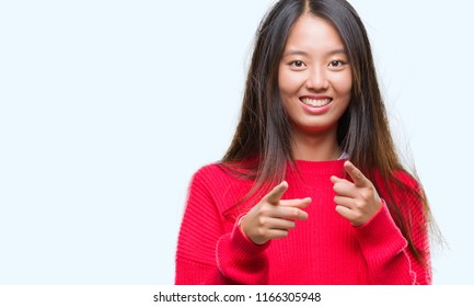 Young asian woman wearing winter sweater over isolated background pointing fingers to camera with happy and funny face. Good energy and vibes.