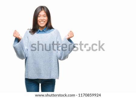 Young asian woman wearing winter sweater over isolated background celebrating surprised and amazed for success with arms raised and open eyes. Winner concept.