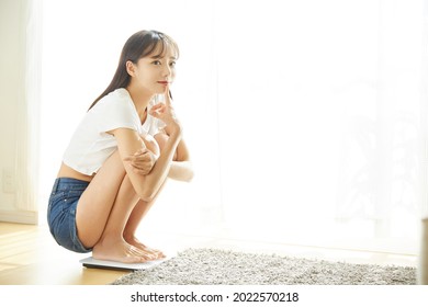 A Young Asian Woman Weighing At Home