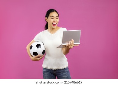 Young Asian Woman In White Shirt Holding Football Ball To Cheering A Soccer Game Online On The Pink Screen Background.