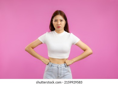 Young Asian Woman In White Top Cop T-shirt Posing Angry On The Pink Screen Background. 