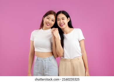 Young asian woman in white t-shirt holding hands together and smiling in a concept of lgbt couple and lesbian on the pink screen background. Pr1de - Powered by Shutterstock