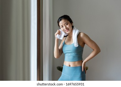 A Young Asian Woman Wipes Sweat With A Towel By The Window
