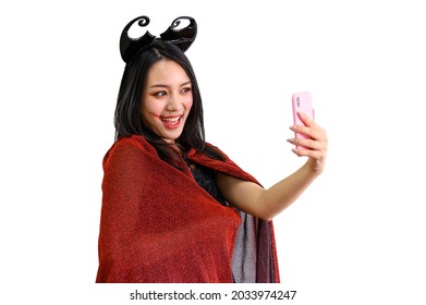 Young Asian Woman In Witch Halloween Costumes With Protection Face Mask Against Coronavirus Taking Selfie Photo On Mobile Phone Isolate On White Background - Halloween On Quarantine Covid-19 Pandemic