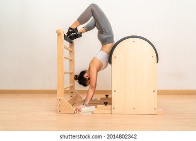 Young Asian woman working hand stand on pilates ladder barrel machine during her health exercise training