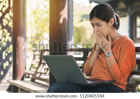 Young asian woman working with her laptop and she feel worried in the park outdoors on vacation time.