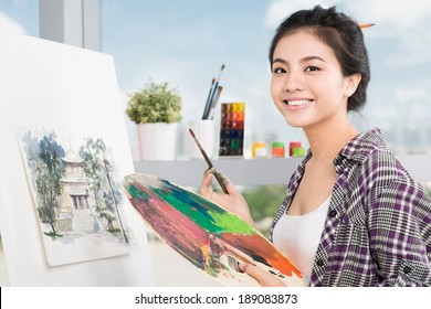 Young Asian woman working on painting in a workshop