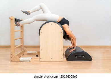 Young Asian woman working on pilates ladder barrel machine during her health exercise training