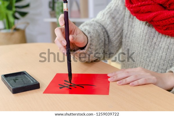 Young\
asian woman writes spring couplet using Chinese calligraphy brush\
and ink stone. It is the tradition of Chinese culture to pastes\
spring couplet to the doors for Chinese New Year.\
