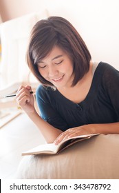 Young Asian Woman Writing Memo Diary Note In Casual Dress.