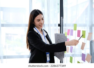 Young asian woman writing text on sticky notes. Brainstorming. - Shutterstock ID 2286377349