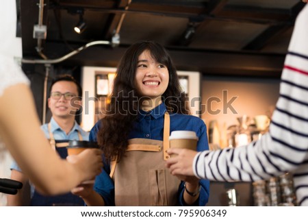 Young asian women barista hold coffee cup serving a client at the coffee shop,start up small business owner food and drink concept.