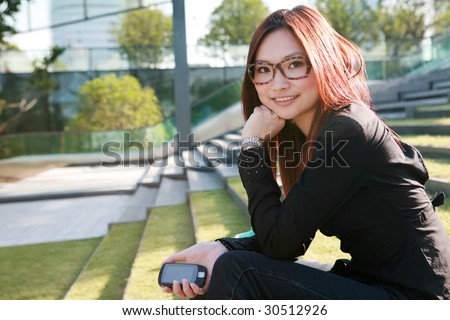 young asian women holding mobile phone sitting on stair