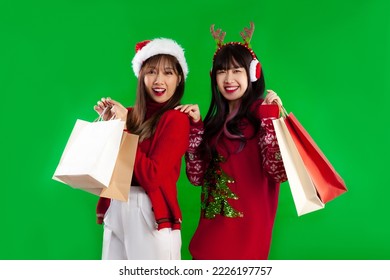 Young asian women long hairstyle lgbtq couple in red sweater in christmas theme clothes carrying paper shopping bags posing on green screen background. Merry Christmas. - Powered by Shutterstock