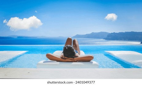 Young Asian women on vacation at Santorini relaxing in a swimming pool looking out over the Caldera ocean of Santorini, Oia Greece, Greek Island Aegean Cyclades during summer in Europe - Powered by Shutterstock