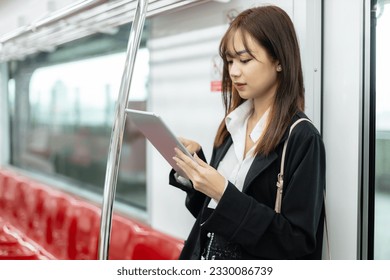 young asian women using tablet during on the way lifestyle travel by train public transportation. Office female commuting to work in morning. Pretty businesswoman passenger journey on railway. - Powered by Shutterstock