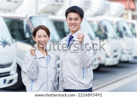 young asian worker pumping fist in front of logistic truck
