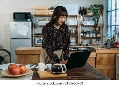 Young Asian youtuber is replying the fans questions online, and announce incoming activities by computer in front of the kitchen.