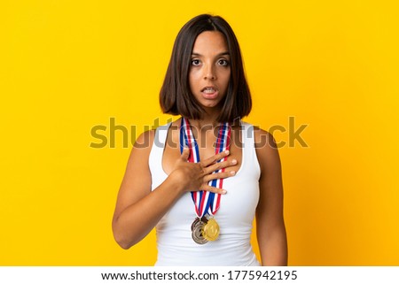 Young asiatic woman with medals isolated on white background surprised and shocked while looking right