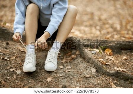 young athlete. beautiful girl athlete tying shoelaces on sneakers in the park. beautiful athlete girl sits tying shoelaces on white sneakers. The concept of a healthy lifestyle.