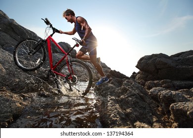 Young athlete crossing water barrier with bicycle