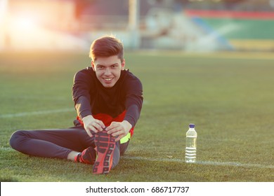 Young athlete doing an exercise in training on a green football field