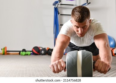 Young athlete exercises the abdominal muscles with the ABS roller - Shutterstock ID 2114756828