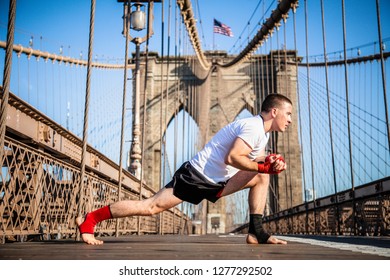 Young athlete fighter exercising and stretching on Brooklyn Bridge in New York City during summer sunny day