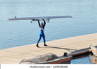 Young athlete guy carries a kayak on the pier to start training on rowing. - Powered by Shutterstock