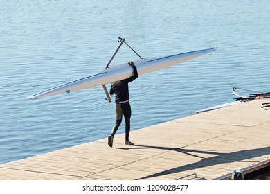 Young athlete guy carries a kayak on the pier to start training on rowing. - Powered by Shutterstock