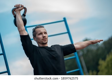 young athlete has workout and doing sport exercises with kettlebell outdoor