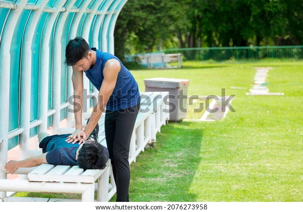 Young athlete making cardiopulmonary\
resuscitation (CPR) to an unconscious young man after heart attack\
while exercising at the sports stadium. Concepts of health care,\
medication and sports.