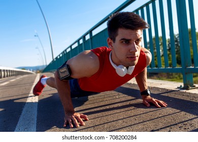 Young athlete man doing push ups on bridge on sunny day.