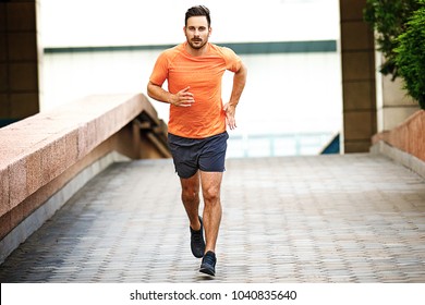 Young Athlete Man Is Jogging In The City.