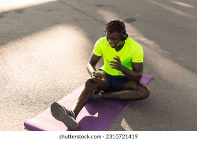 Young athlete man listening music while resting after training. Handsome African man training outside. - Shutterstock ID 2310721419