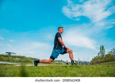 Young Athlete Man Streching In The Park Outdoor. Male Runner Warm Up Ready For Jogging On The Road Outside