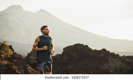 Young Athlete Man Trail Running In Mountains In The Morning. Healthy Lifestyle Concept. Panoramic Photo With Empty Copy Space.