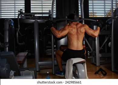 Young Athlete With Muscular Body Working Out On Pull Down Machine At Gym