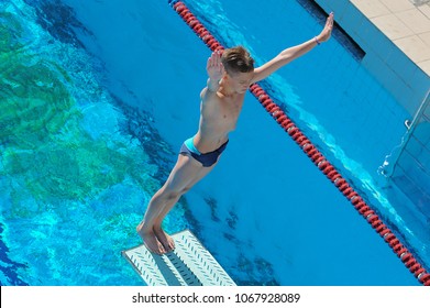 
young athlete on a meter springboard in the open pool. Boy starts diving in  water. hands up, rear stance jump position - Powered by Shutterstock