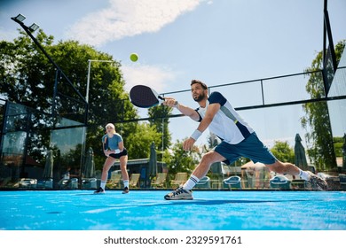 Young athlete playing padel in mixed doubles on outdoor court. Copy space. - Powered by Shutterstock