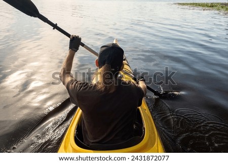 Young athlete propels forward gracefully paddling on river surface. With zeal man ushers in summer season of aquatic sports