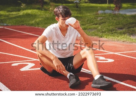 Similar – Image, Stock Photo Young athlete refreshes himself with water after a hard workout on the athletic oval in the intense heat. Endurance training. Brown-haired adolescent